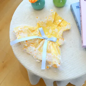 Detail of floral daisy embroidery and blue ribbon bow on yellow dog summer dress