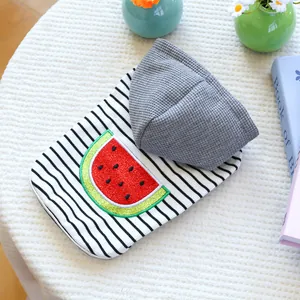 Detail of pet hoodie with striped pattern and embroidered watermelon patch on white fur