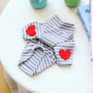 Detail of striped pet sweater featuring red heart patches on sleeves and knit fabric texture