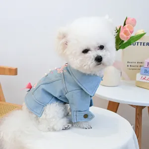 Detail of light blue denim pet jacket with pink bow embroidery and pearl accents