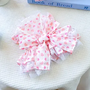 Detail of pink dog dress featuring red hearts, large bow, and white lace trim