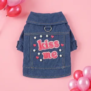 Blaue Hundejeansjacke mit Kiss Me Stickerei und Perlenverzierung auf rosa Hintergrund