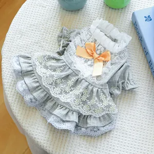 Detail of green plaid dog dress with white lace trim and orange satin bow