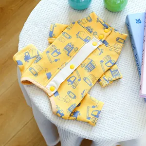 Close-up of yellow dog jumpsuit with blue construction truck prints on white knit fabric
