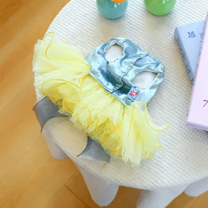 Détail de la robe satinée pour chien avec jupe en tulle jaune et boutons dorés