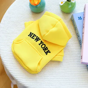 Close-up of a bright yellow New York hoodie for dogs on a white textured background
