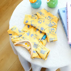 Detail of yellow dog sweatshirt featuring cartoon truck prints and dual snap buttons