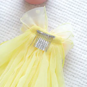 Macro detail of yellow pet wedding veil with heart pattern and metal comb insert