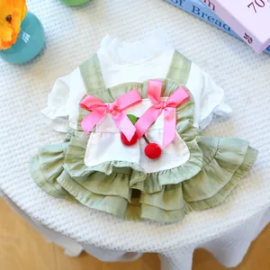 Détail de robe pour animal avec cerises, nœuds roses et ourlet plissé vert sur gaufre