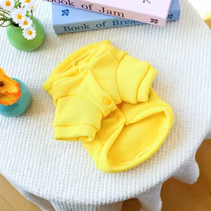 Close-up of a bright yellow fleece dog hoodie with buttons on a textured white background
