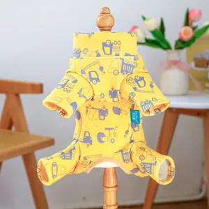 Detailed view of yellow pet onesie featuring cartoon truck prints and soft cotton fabric