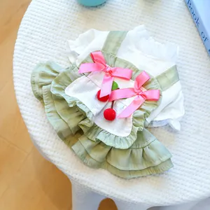 Détail de la robe pour chien avec nœuds en satin rose et cerises sur la jupe