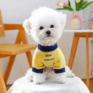 Detail of yellow dog vest with navy Goal Hunter print on a small white dog