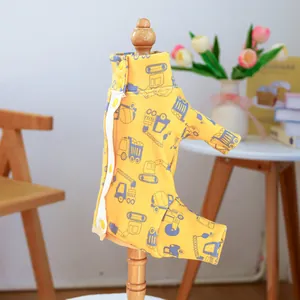 Close-up of yellow pet jumpsuit with construction vehicle prints on a wooden hanger