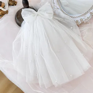 Detailed view of elegant white dog wedding veil with bow and faux pearls for small pets