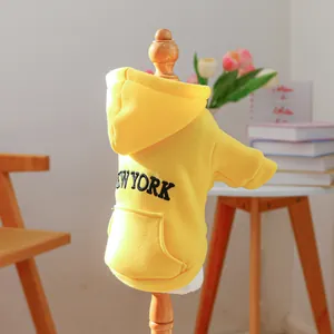 Close-up of a yellow dog hoodie with New York lettering on a wooden pet mannequin