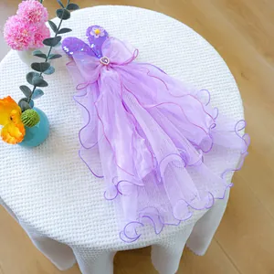 Detail of purple mesh dog dress with sequins, bow, and heart button on white table