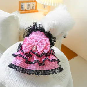 Detail of pink plaid pet dress featuring black lace layers and a jewel bow on a dog