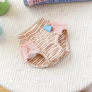 Dettaglio dei pantaloni a righe per cani con pizzo rosa e fiocco su pelliccia bianca