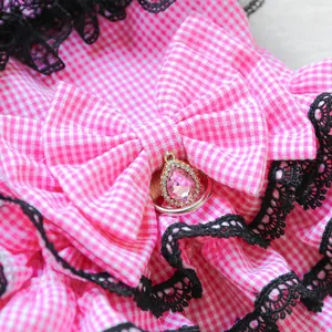 Detail of pink gingham dog dress with black lace trim and crystal bow pendant