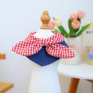 Detail of pet bib with red checkered bow and denim triangle scarf on a model