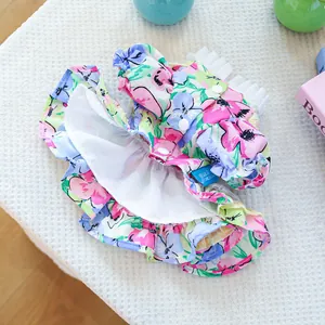Detailed view of floral pet dress featuring white snap buttons and blue brand tag