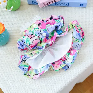 Close-up of floral pet dress with ruffle collar and button details on a white textured cloth