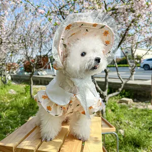 Detailed view of floral pet sun hat with lace trim on cherry blossom background