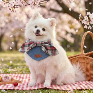 Plaid bowtie pet bandana with leather logo on denim bib, outdoor cherry blossom setting