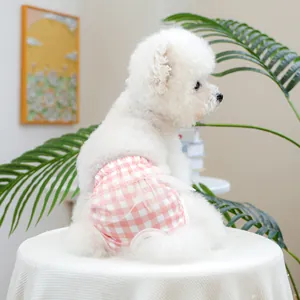 Dettaglio dei pantaloni igienici rosa a quadretti con pizzo su un cane Bichon bianco