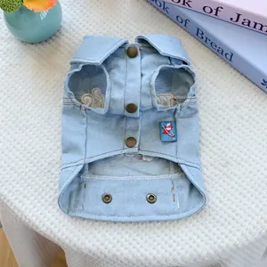Close-up of light blue denim pet vest featuring metal snap buttons and woven label