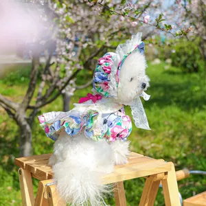Detail of floral dog dress with sun hat and pink bow in spring cherry blossom garden
