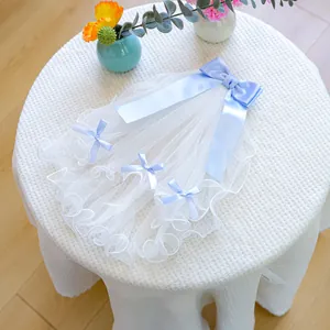 Detailed view of white pet wedding veil with light blue ribbon bows on waffle fabric