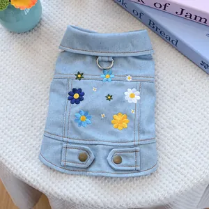 Detail of light blue denim dog vest featuring floral embroidery and a metal D-ring attachment