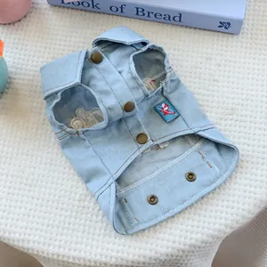 Close-up of light blue denim pet vest with brass buttons and cartoon label detail