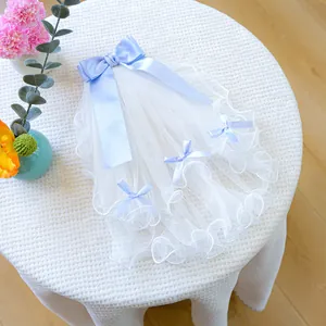 Detailed view of white pet wedding veil with elegant light blue satin bows on table