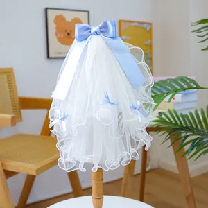 Close-up of white lace pet wedding veil with light blue ribbon bows and wavy edges