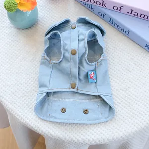 Detailed close-up of light blue denim dog vest featuring metal buttons and twill texture
