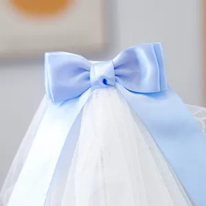 Close-up of a white pet wedding veil with a light blue satin bow and delicate mesh detail
