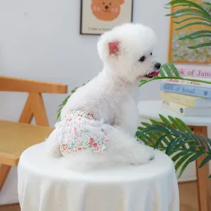 Dettaglio dei pantaloni igienici floreali per cani con pizzo bianco su un piccolo cane bianco