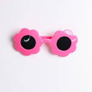 Occhiali da sole per bambini a forma di fiore rosa con lenti scure su sfondo bianco