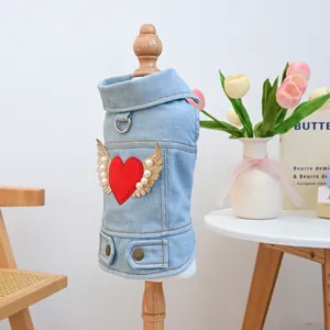 Detail of blue denim pet vest featuring a red heart with golden wings and pearl accents