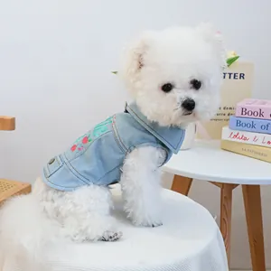 Detail of light blue denim pet vest with cherry embroidery on a white dog