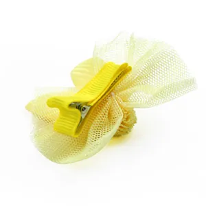 Detailweergave van de gele mesh strik haarclip met een met lint omwikkelde snavelclip