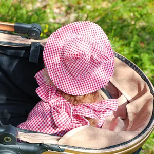 Close-up of a small dog wearing a red and white checkered sun hat and matching outfit