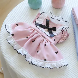 Dettaglio vestito rosa per animali con cuori, fiocco nero e ciondolo dorato a cuore
