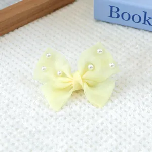 Détail d'un nœud en organza jaune clair orné de perles blanches sur tissu en maille