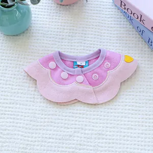 Detail of flower-shaped pet bib with scalloped edges and heart patch on a soft textured base