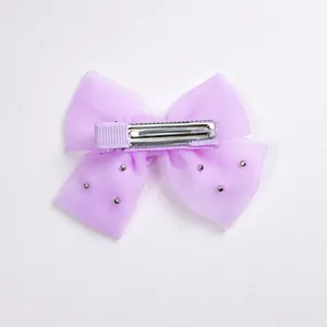 Détail d'une barrette à nœud en organza violet avec clous et pince à bec de canard