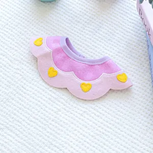 Detail of pink and purple pet bib with yellow heart embroidery on white soft texture